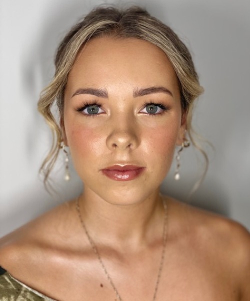 formal-makeup-soft-glam-blonde Blonde young woman with styled curly blonde side fringe, soft glam nude makeup and pearl drop earrings for formal shoot.